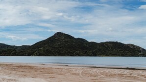 A beach with a mountain in the background. - Omoho Stream X by Tiny Away (Kennedy Bay)