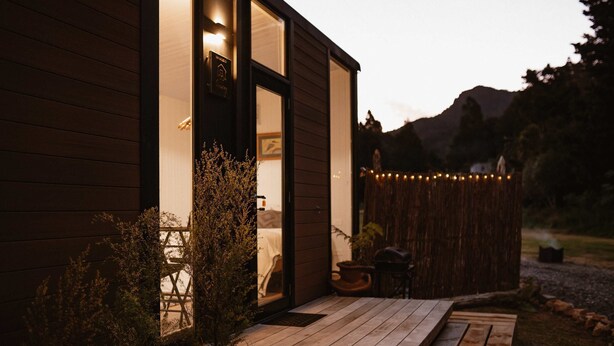 A wooden building with a deck, a door, and a window. - Omoho Stream X by Tiny Away (Kennedy Bay)