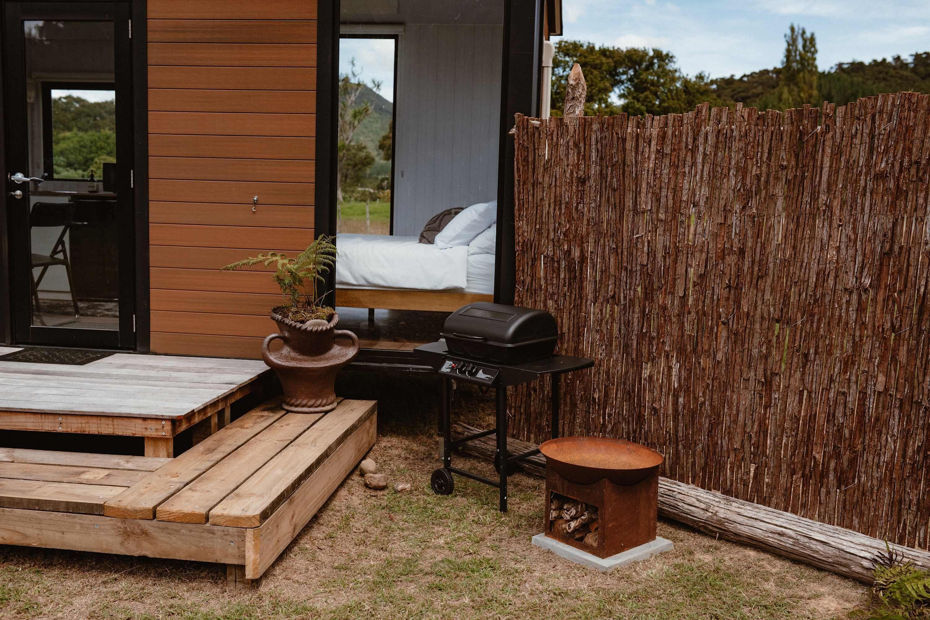A wooden deck with a grill, a small table, and a seating area with a view of a bedroom.