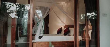 A bedroom with a wooden bed, white bedding, and a canopy.