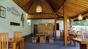 A restaurant with wooden furniture, a thatched roof, and wall decorations. - Abimana Ubud (Payangan)