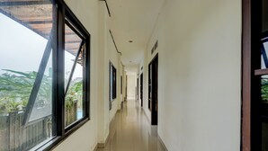 Un pasillo con ventanas amplias, suelo de baldosas y puertas a ambos lados.