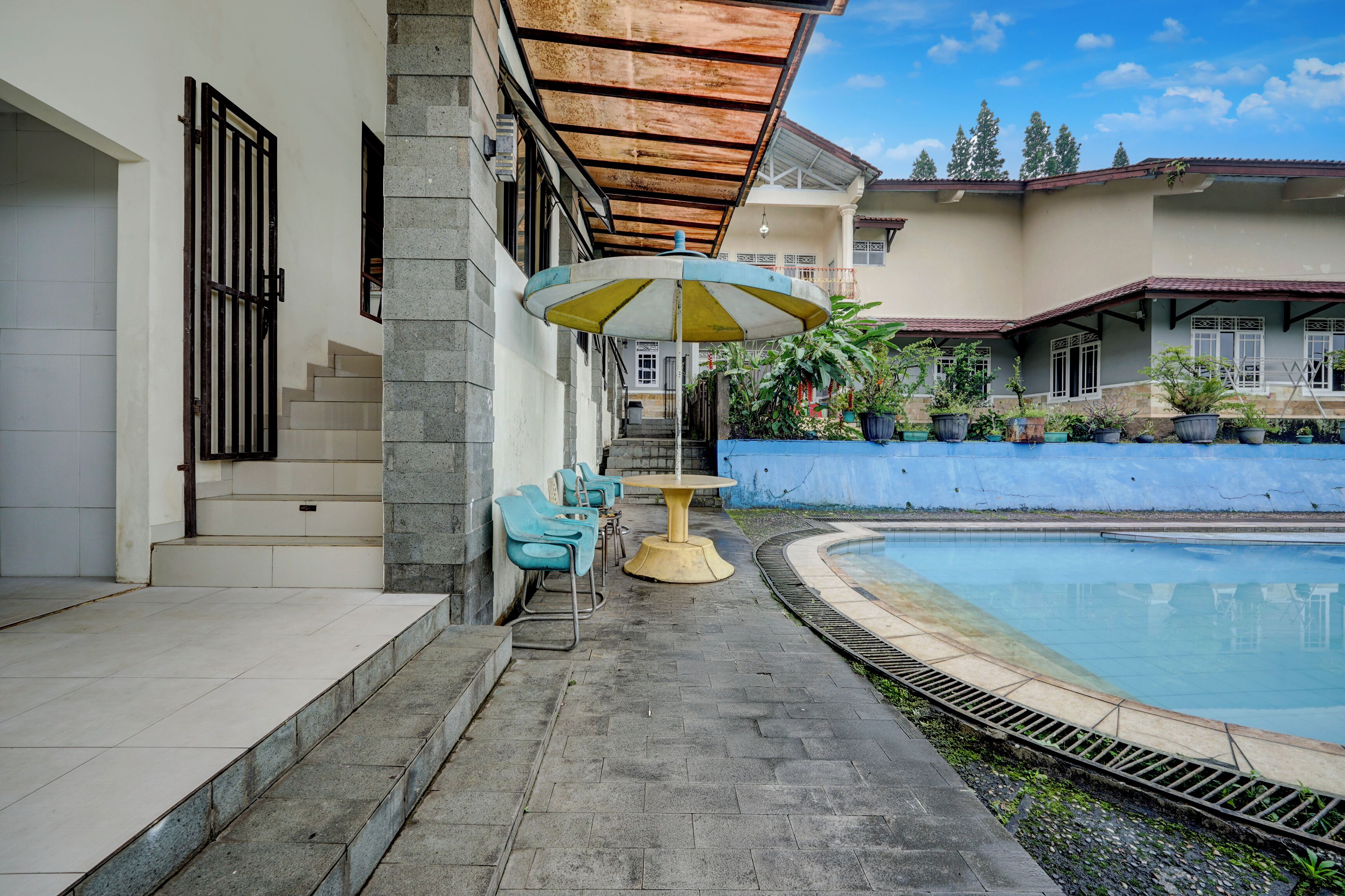 A poolside area with a covered seating area, a staircase, and potted plants.
