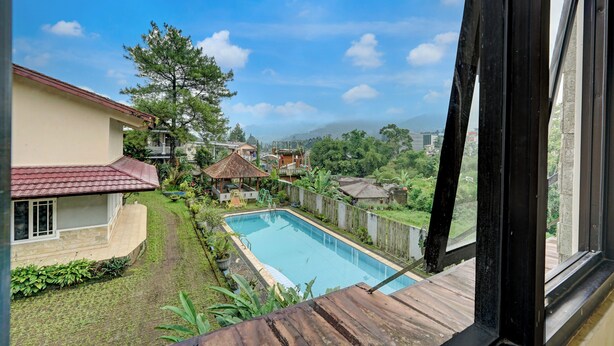 Vista de una piscina, una casa y un jardín desde una ventana.