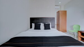 Una habitación de hotel con una cama, un armario de madera, una silla verde y un escritorio.