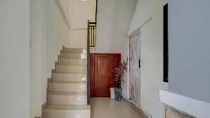 Una escalera que lleva a una puerta de madera, una planta en maceta y un muro de piedra.