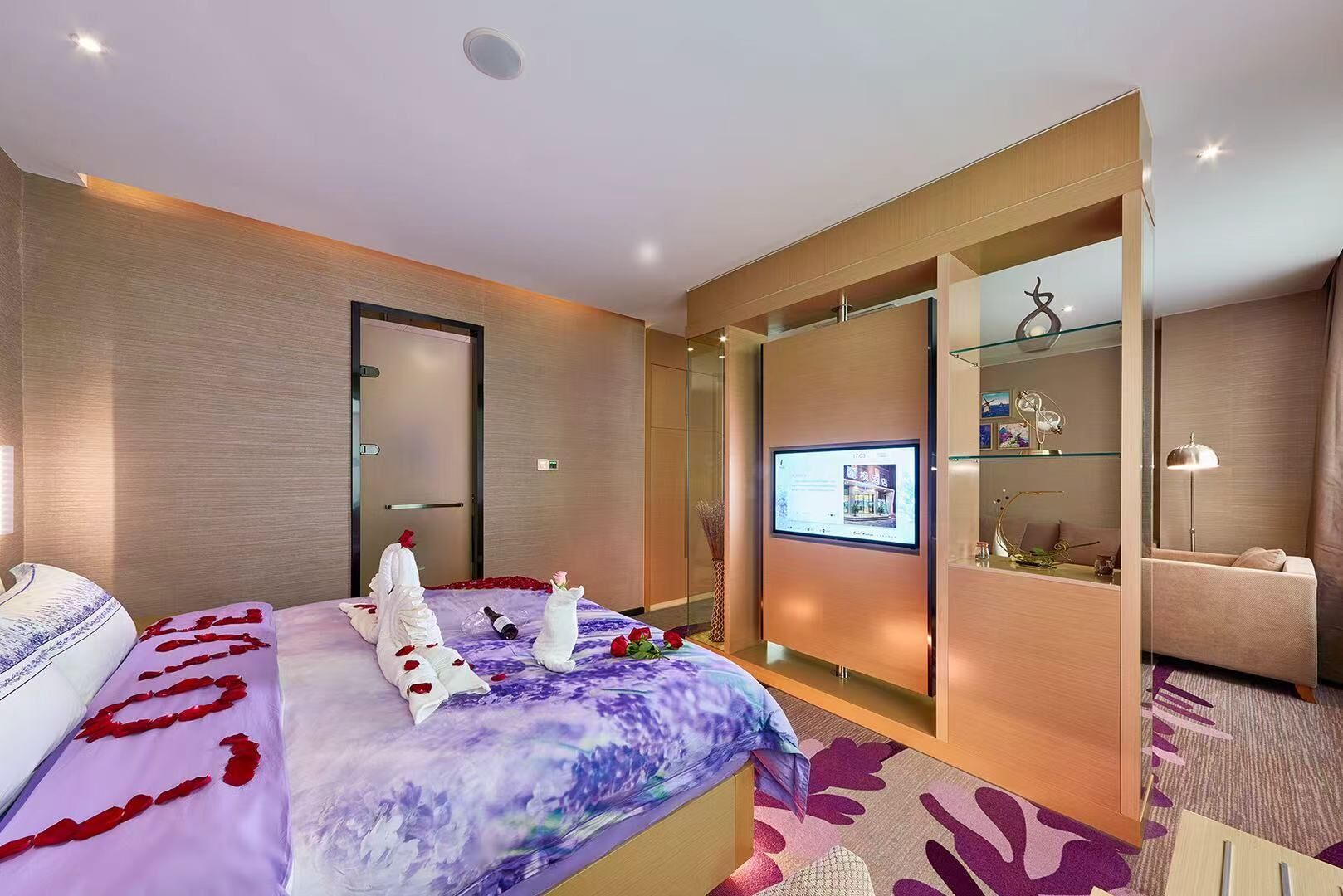 A modern hotel room with a bed, a TV, a desk, and a sofa.