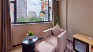 A modern hotel room with a large window, a comfortable chair, a small table with a plant, and a desk with a television. - Lavande International Hotel Pazhou Convention & Exhibition Center Eastxiaonan Metro Station Branch - Free Deliver Service to Guangzhou Baiyun International Airport & Free Shuttle Bus to Canton Fair Complex During Canton Fair Period (Guangzhou)