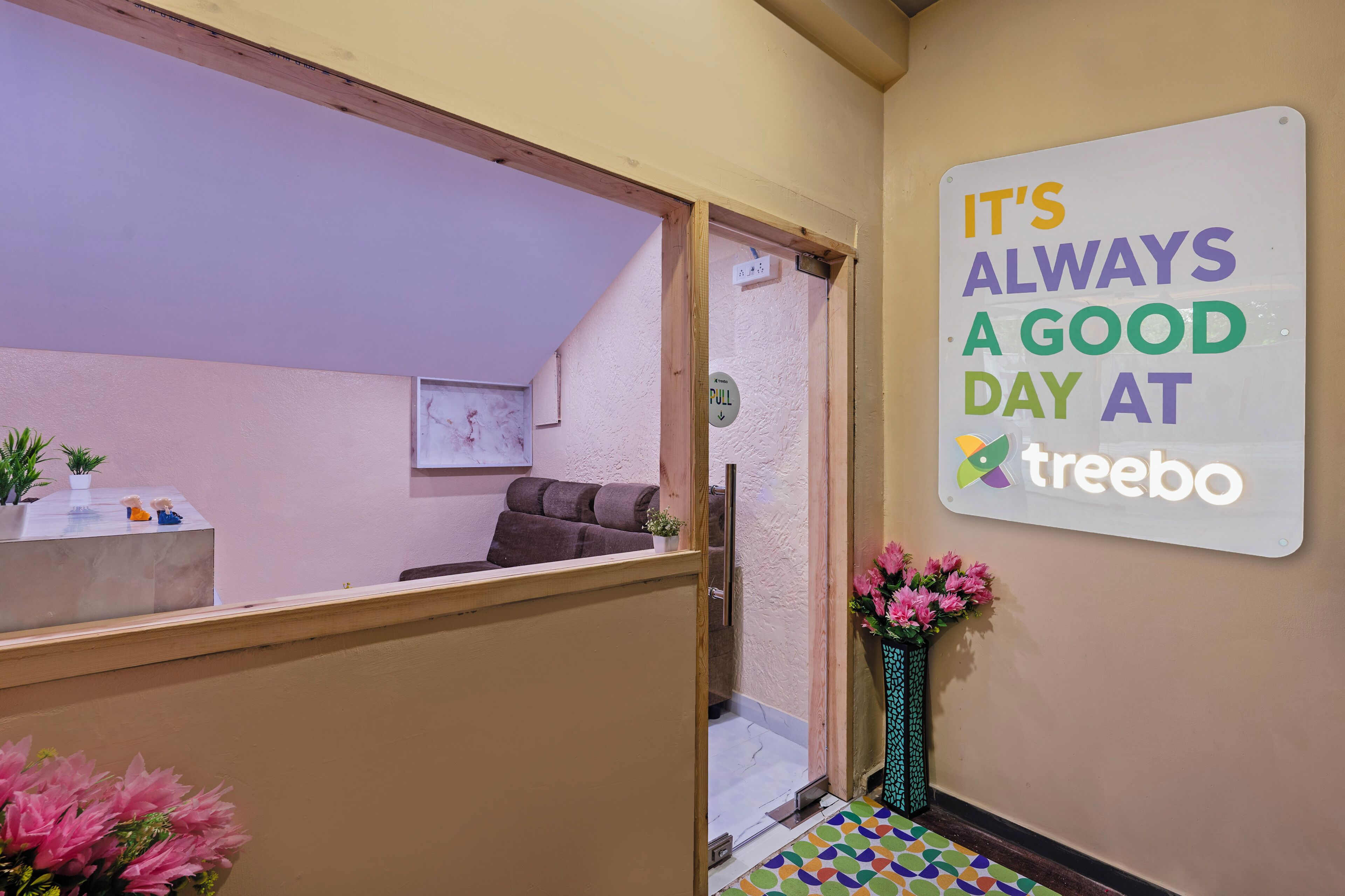 Zona de recepción de hotel con un cartel que dice 'IT'S ALWAYS A GOOD DAY AT treebo'.