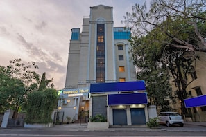 A hotel with a central tower, a sign for 'treebo TOUR,' and a parked car. - Treebo GT Meridian, T-Nagar (Chennai)