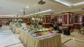 A buffet setup with various food items and a projector on the ceiling. - Al Shohada by Palm Rich Makkah EX - Al Shohada Hotel (Makkah)