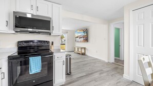 A modern kitchen with white cabinets, a black stove, and a stainless steel microwave. - Lovely 3-bedroom cottage with AC in peaceful Hudson (Hudson)