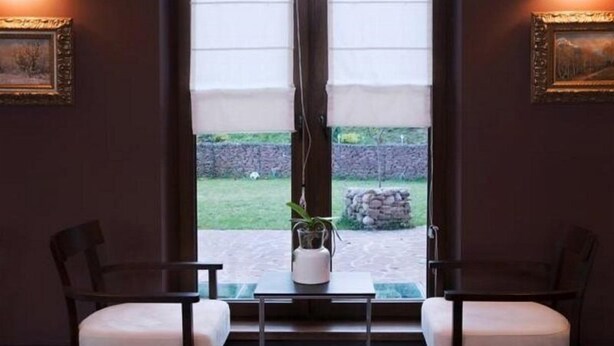 A room with two chairs and a small table, a window with curtains, and framed pictures on the walls. - 6ato Hotel Sofia (Sofia)