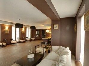 A modern living room with a sofa, chairs, a coffee table, and a dining area with chairs and a table. - 6ato Hotel Sofia (Sofia)