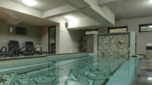 A swimming pool with a patterned floor, a seating area with chairs, and a wall-mounted television. - 6ato Hotel Sofia (Sofia)