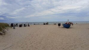 En strand med flera båtar, en sandstrand och en molnig himmel.