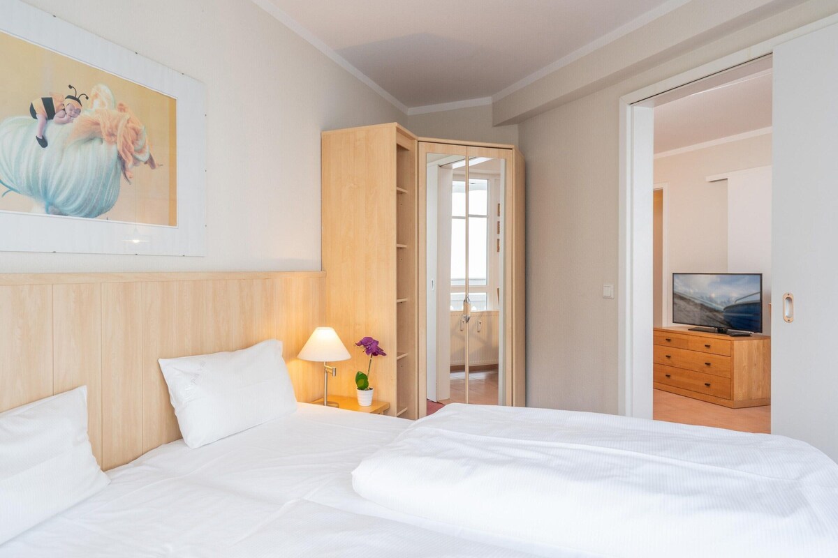 Ein Hotelzimmer mit einem Bett, einem Nachttisch mit Lampe, einem Fernseher und einem Holzschrank.