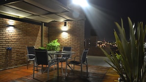 An outdoor patio with a brick wall, a table with chairs, and a potted plant. - Kube Apartment Express (Córdoba)