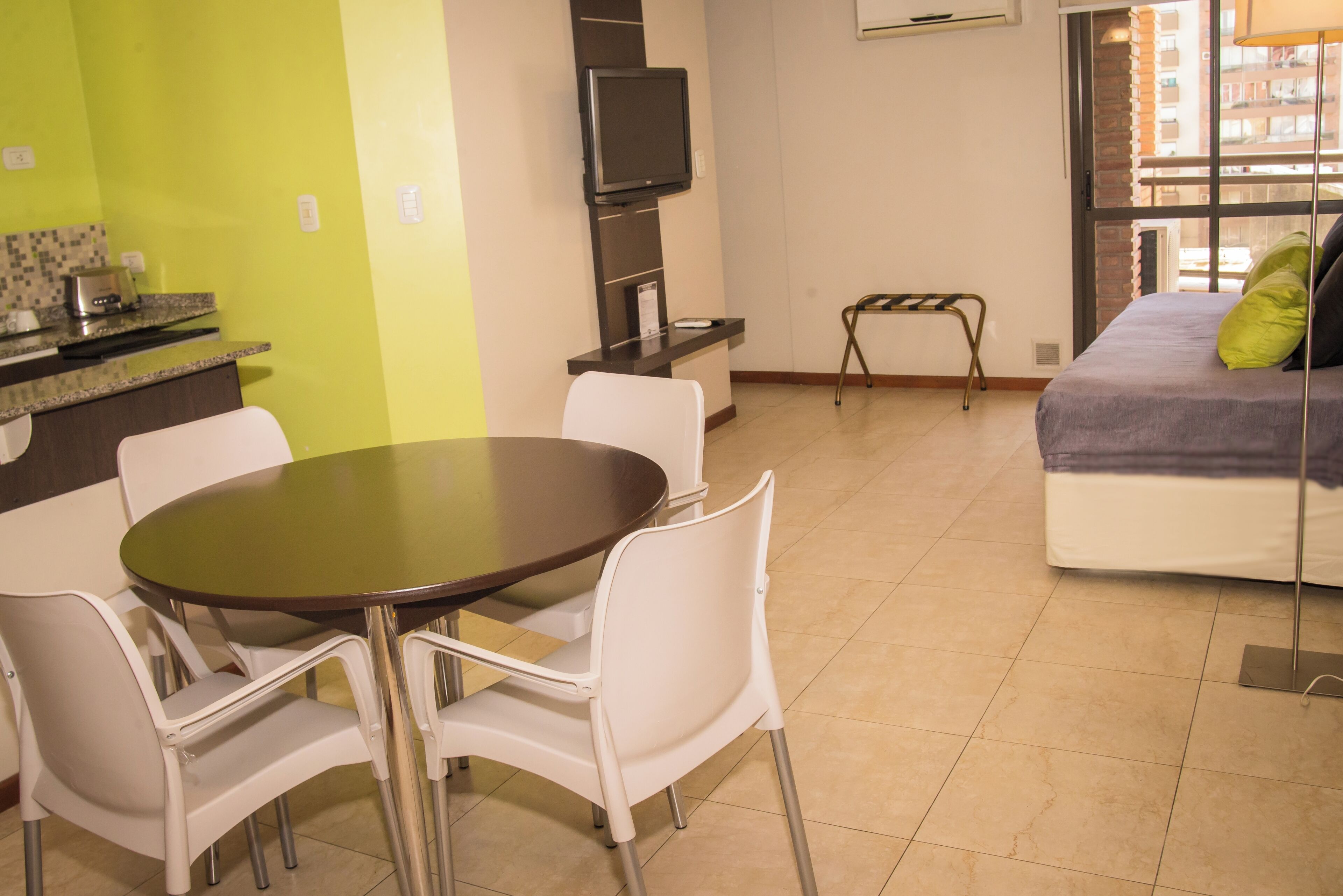 A compact living space with a dining area, a bed with pillows, a television, and a view through a window.