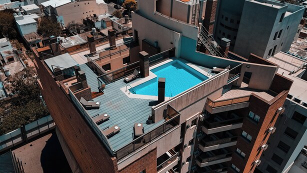 A rooftop pool with a rectangular shape, surrounded by a balcony with seating and a fire pit. - Kube Apartment Express (Córdoba)