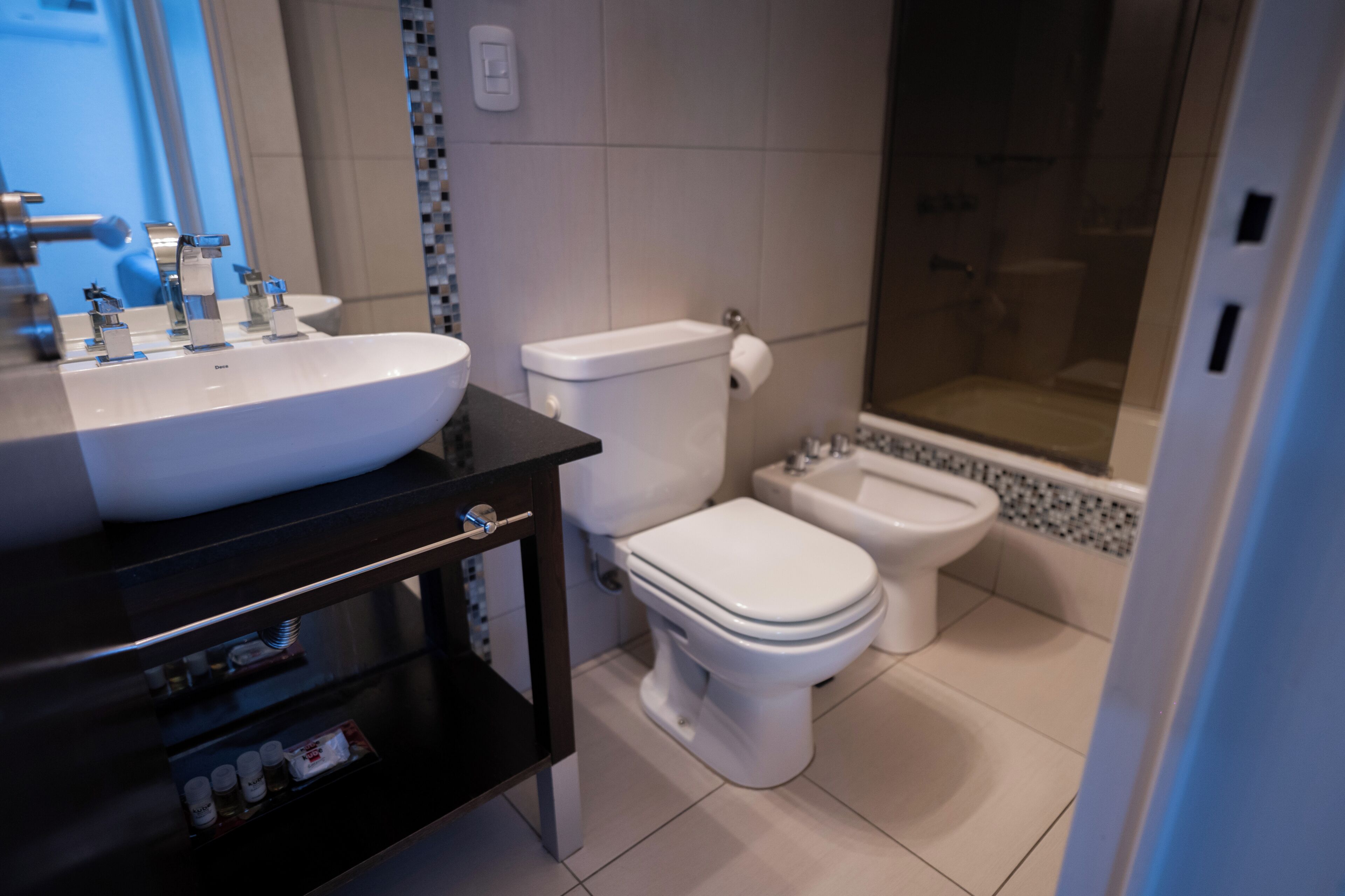 Een moderne badkamer met een groot wit wastafel, toilet en een douchetoilet.