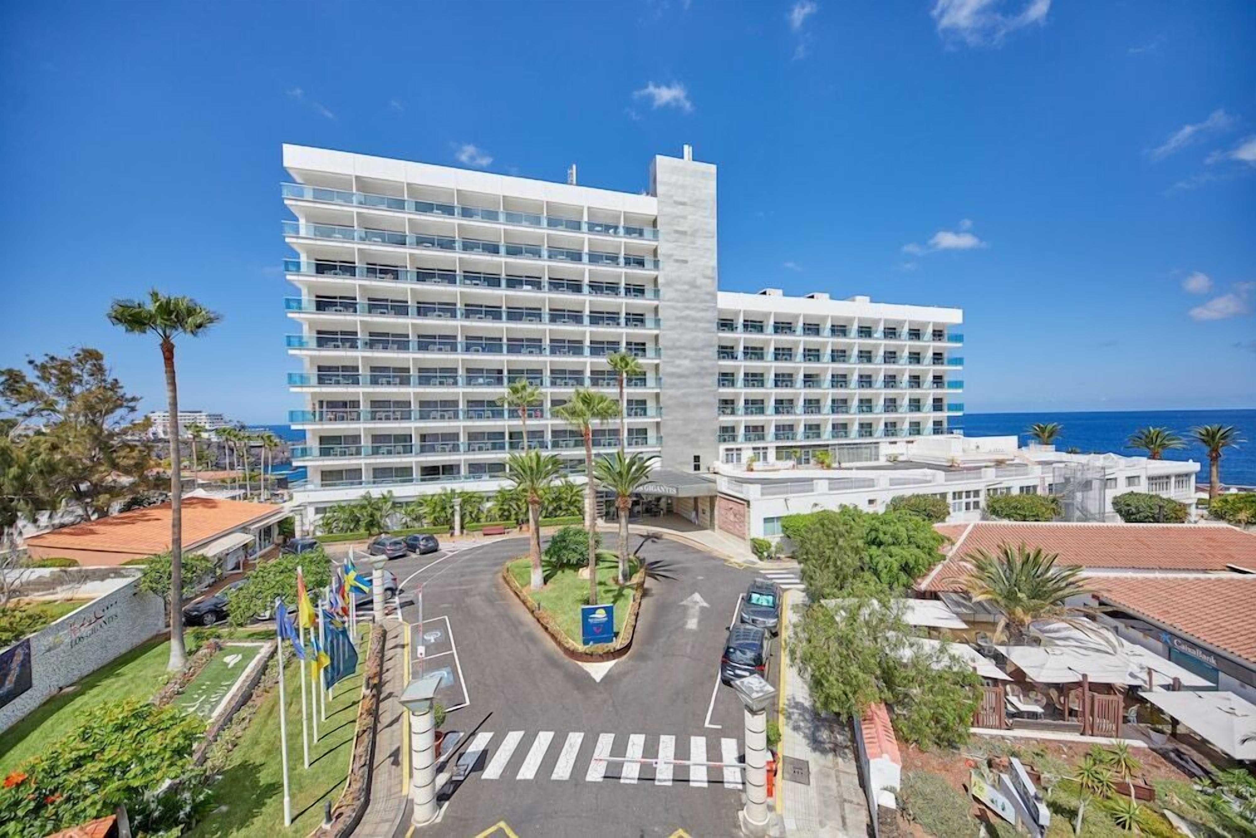 Un hotel moderno con varios pisos, un patio central y vista al océano.