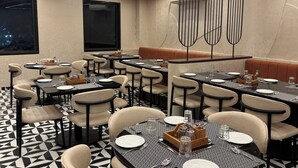 Un restaurante con varias mesas, sillas y un diseño moderno en el techo.
