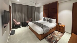 Un dormitorio moderno con una cama grande, un ventilador de techo, una mesita de noche y un televisor.