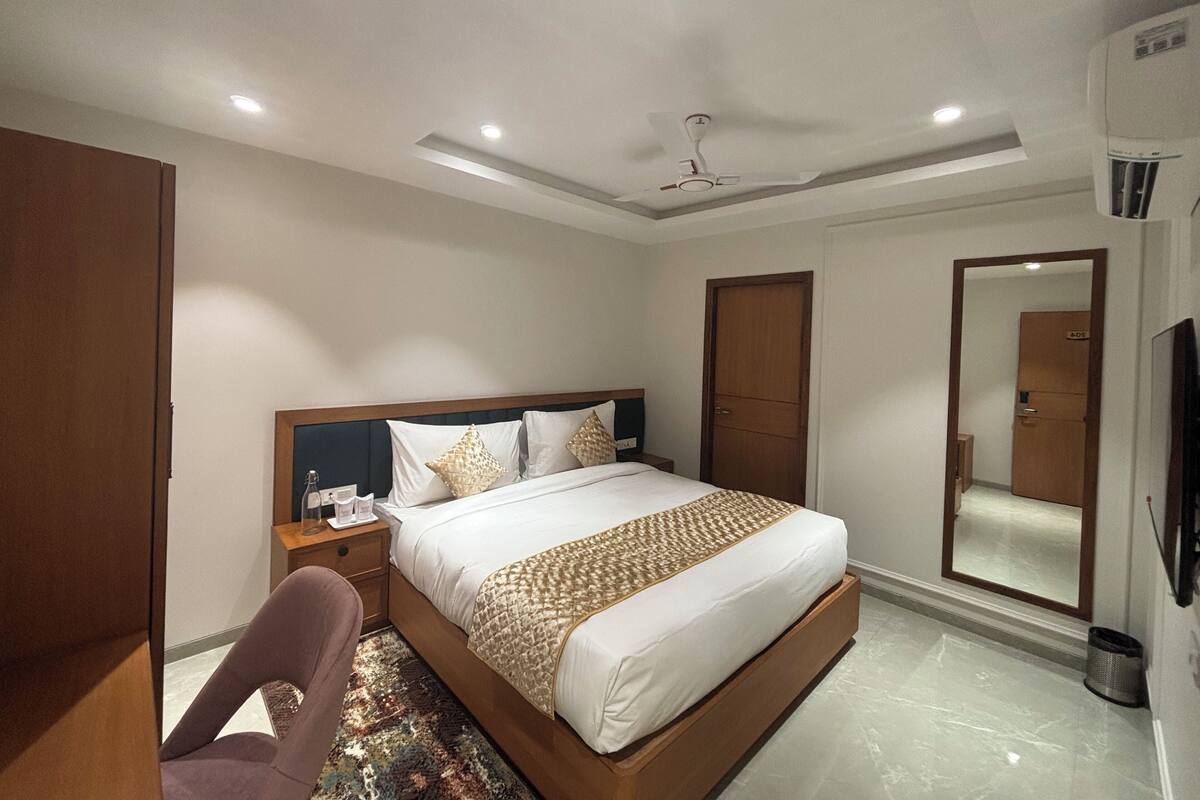 A hotel room with a bed, a chair, a nightstand, a mirror, and a ceiling fan.