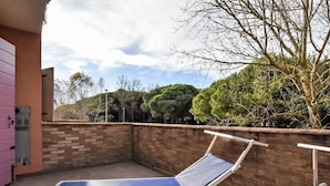 Une terrasse sur le toit avec deux chaises longues bleues, un mur de briques et une vue sur des arbres et un bâtiment en arrière-plan.