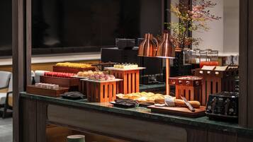 A buffet setup with various food items and a coffee machine.