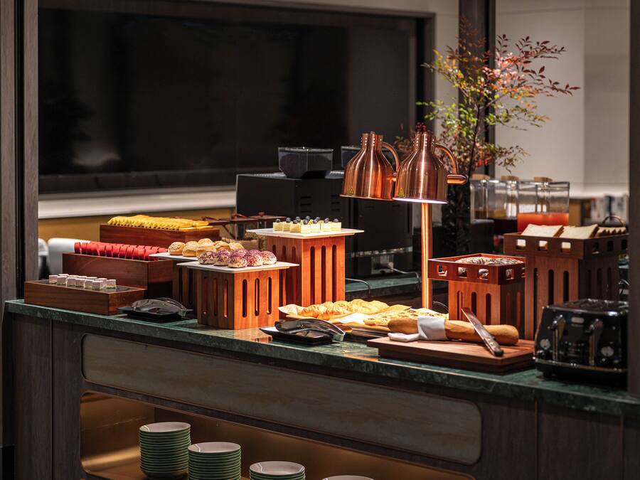 A buffet setup with various food items and a coffee machine.