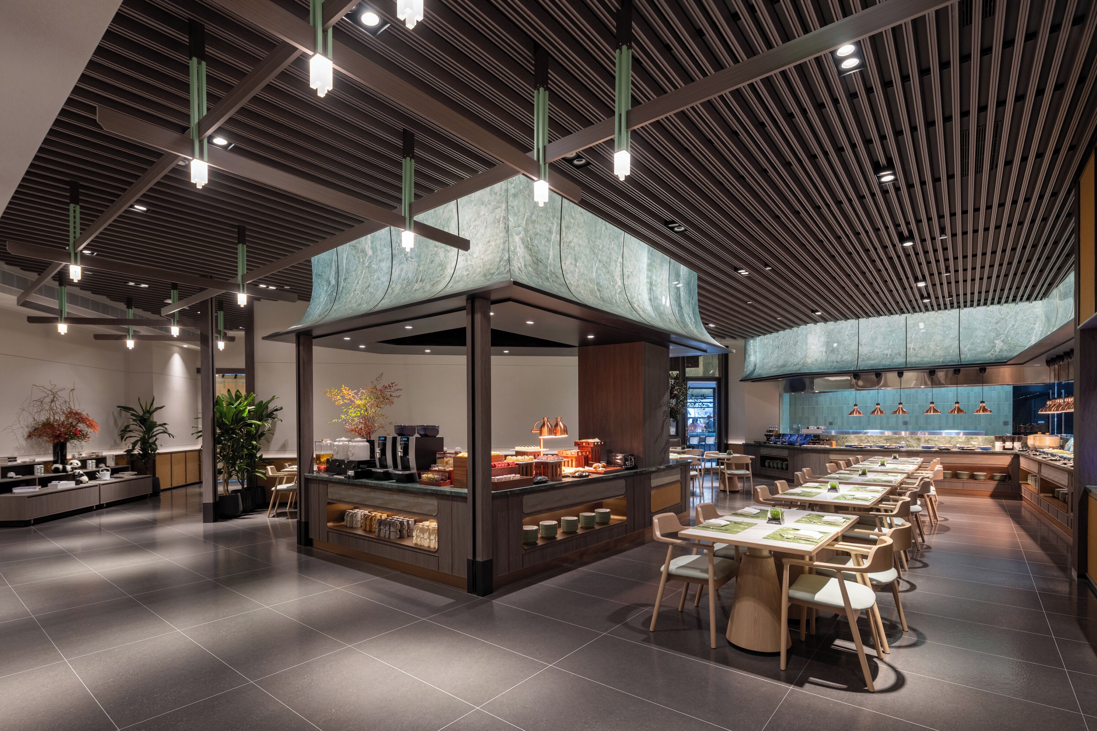 A modern restaurant with a central bar area, multiple dining tables, and a high ceiling with linear lighting fixtures.