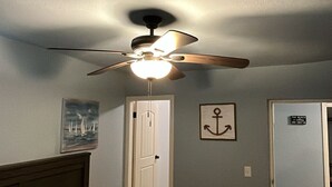 A bedroom with a bed, a ceiling fan, a door, and a wall with a framed picture and a sign. - Your coastal escape starts here! (Playas de Rosarito, BC Mexico)