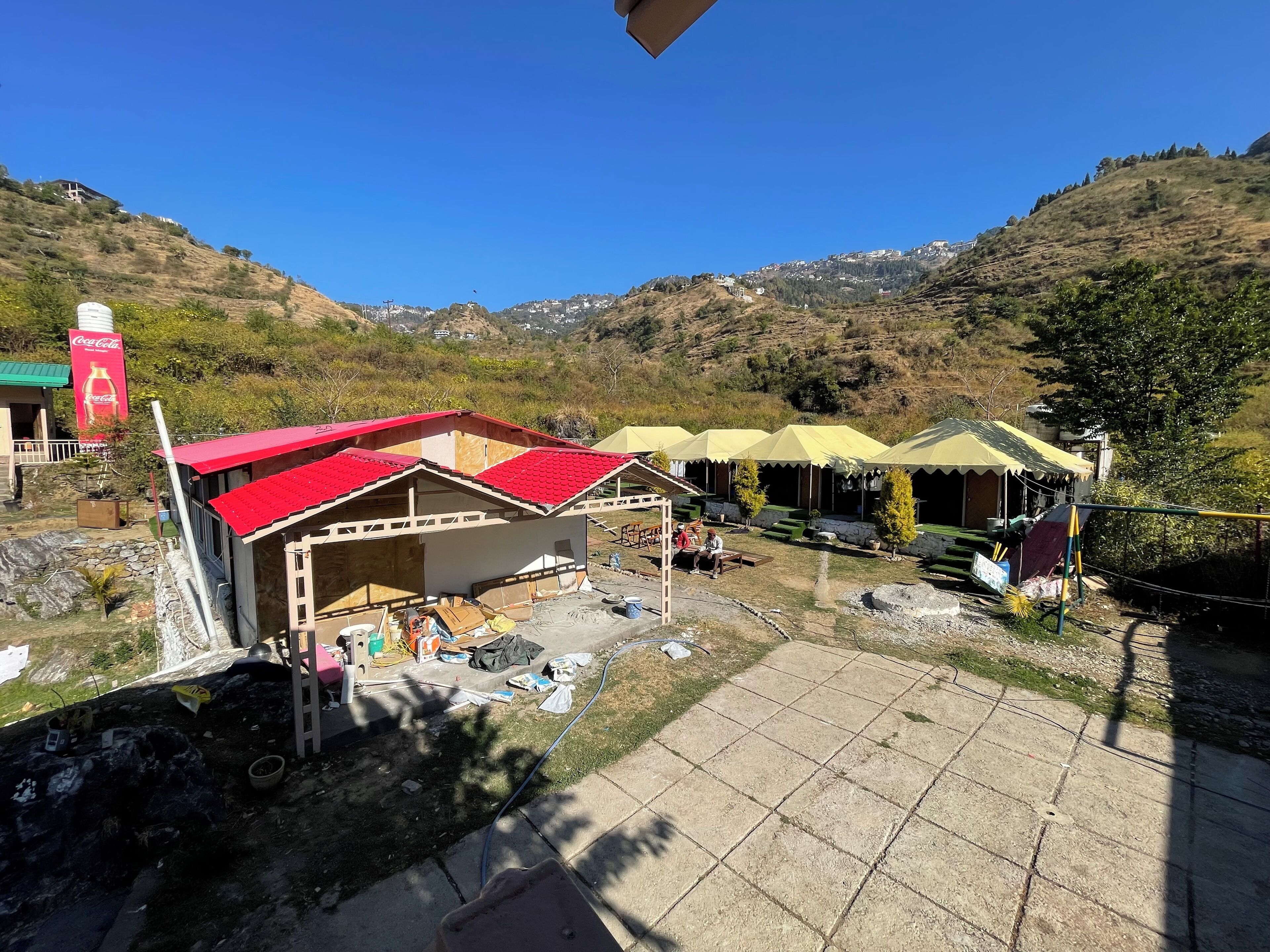 A building with a red roof, a Coca-Cola sign, and a view of a mountainous landscape.