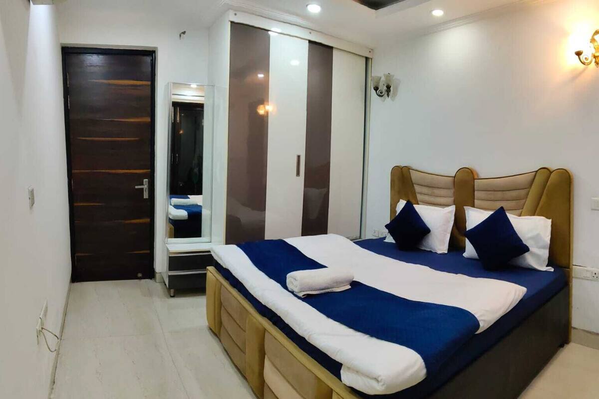 A bedroom with a bed, a wardrobe, a mirror, and a wall-mounted light fixture.