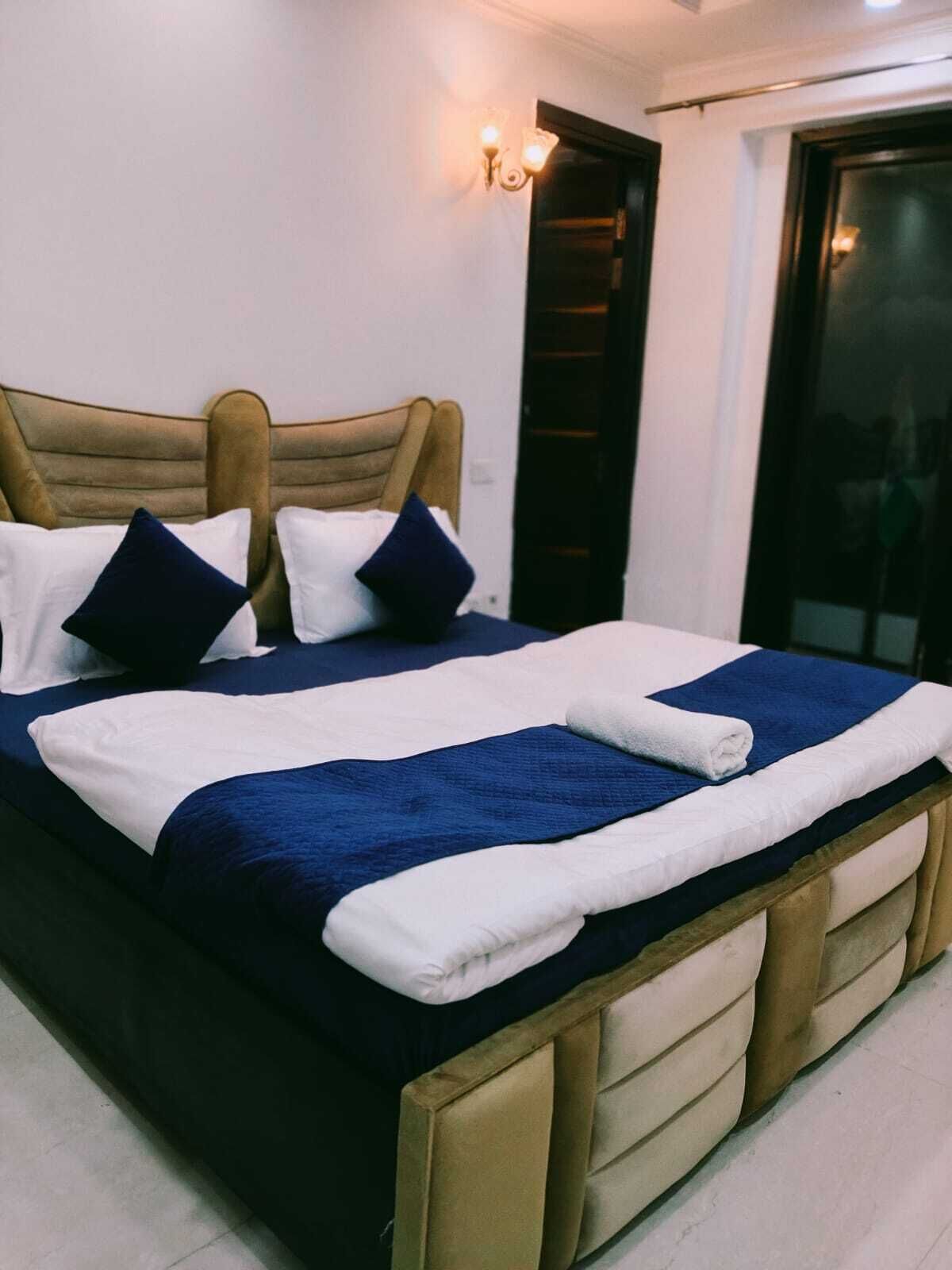 A neatly made bed with a blue and white bedspread, two pillows, and a wooden headboard.