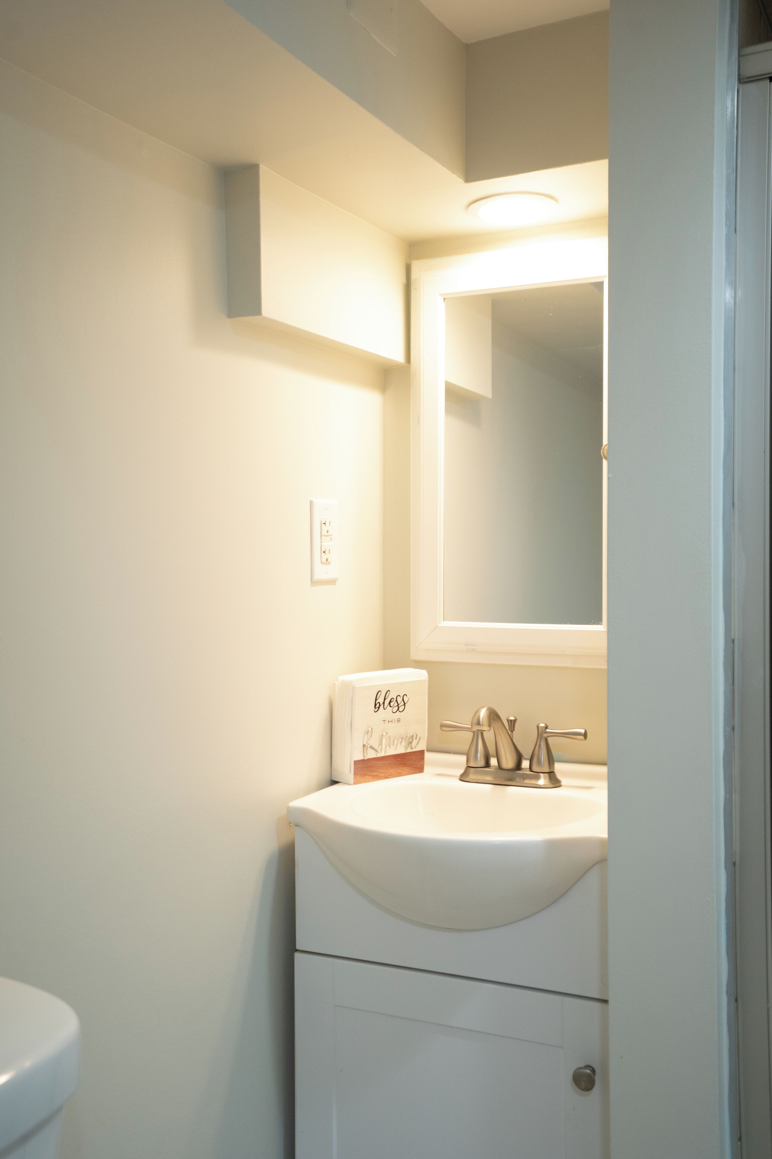 A bathroom with a white sink, a mirror above it, and a toilet to the left.