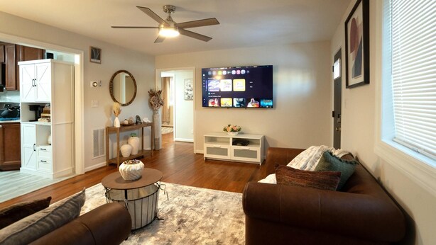 A modern living room with a flat-screen TV, a ceiling fan, and a dining area with a white cabinet. - Modern 4BR Severn Home • 10 Min to BWI • Near Fort Meade • Sleeps 8 (Severn)