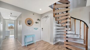Ein modernes Interieur mit einer Holzspirale, einem zur Toilette führenden Gang und einem kleinen, blauen Beistelltisch.