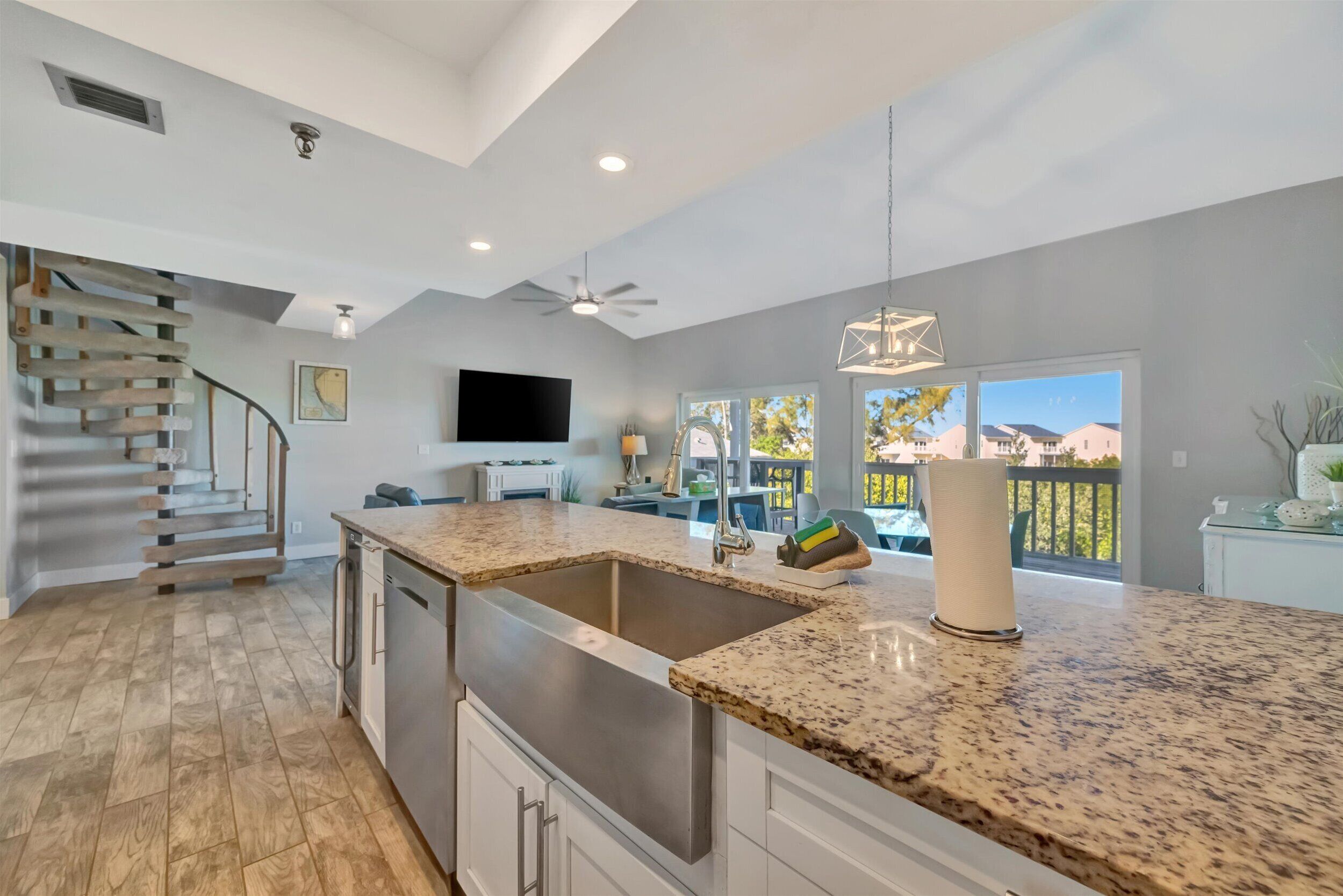 A modern kitchen with a granite countertop, stainless steel appliances, and a large window offering a view of the outdoors.