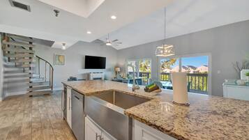 A modern kitchen with a granite countertop, stainless steel appliances, and a large window offering a view of the outdoors.
