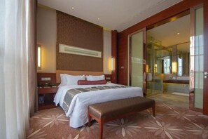 A hotel room with a large bed, bedside tables, a bench, a mirror, and a sliding glass door leading to a bathroom. - Howard Johnson By Wyndham Puhui Plaza Chongqing (Chongqing)