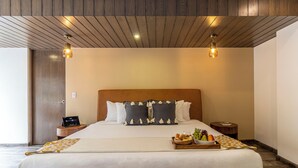 A hotel room with a wooden ceiling, a large bed with a headboard, bedside tables, and a tray with fruits and bread. - Hotel Boutique Kooben  (Merida)