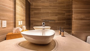A modern bathroom with a large vessel sink, two faucets, and a wooden vanity. - Hotel Boutique Kooben  (Merida)