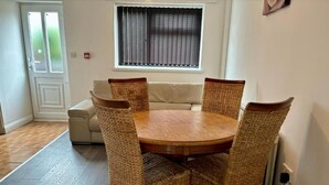 A dining area with a round wooden table and four wicker chairs. - Family Ensuite in Dudley (Dudley)