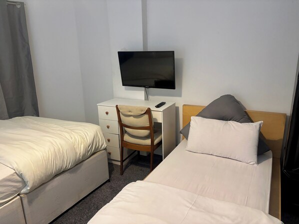 A hotel room with two beds, a desk with a TV, and a chair. - Family Ensuite in Dudley (Dudley)