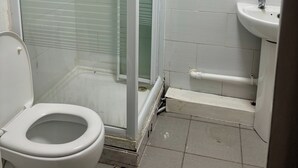 A small, basic bathroom with a toilet, a shower area, and a sink. - Family Ensuite in Dudley (Dudley)