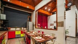 Ein Essbereich mit einem Holztisch, gedeckt für vier Personen, roten Stühlen und einer Küche im Hintergrund.