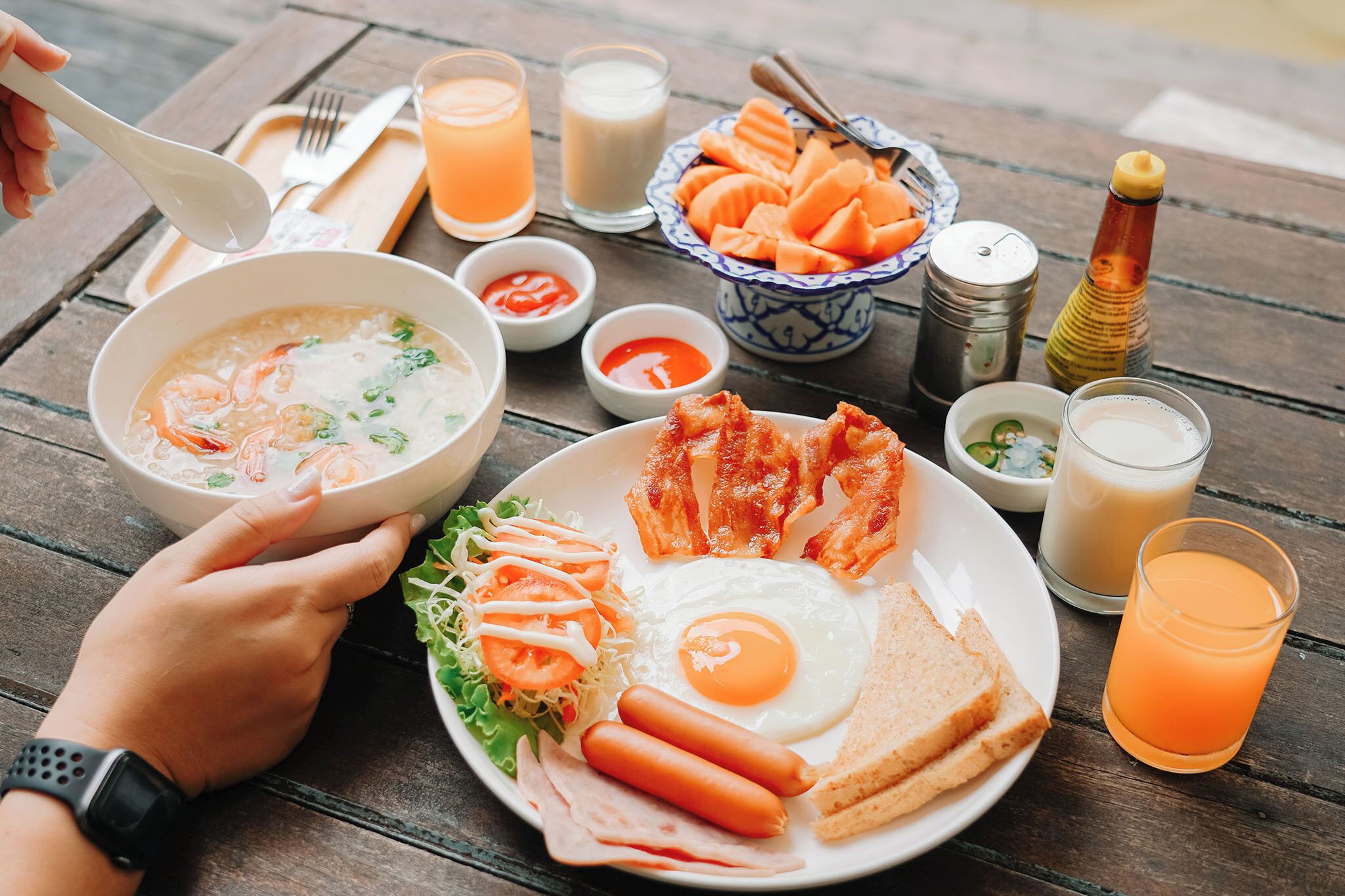 Una mesa con un plato que incluye sopa, tocino, huevos y verduras.